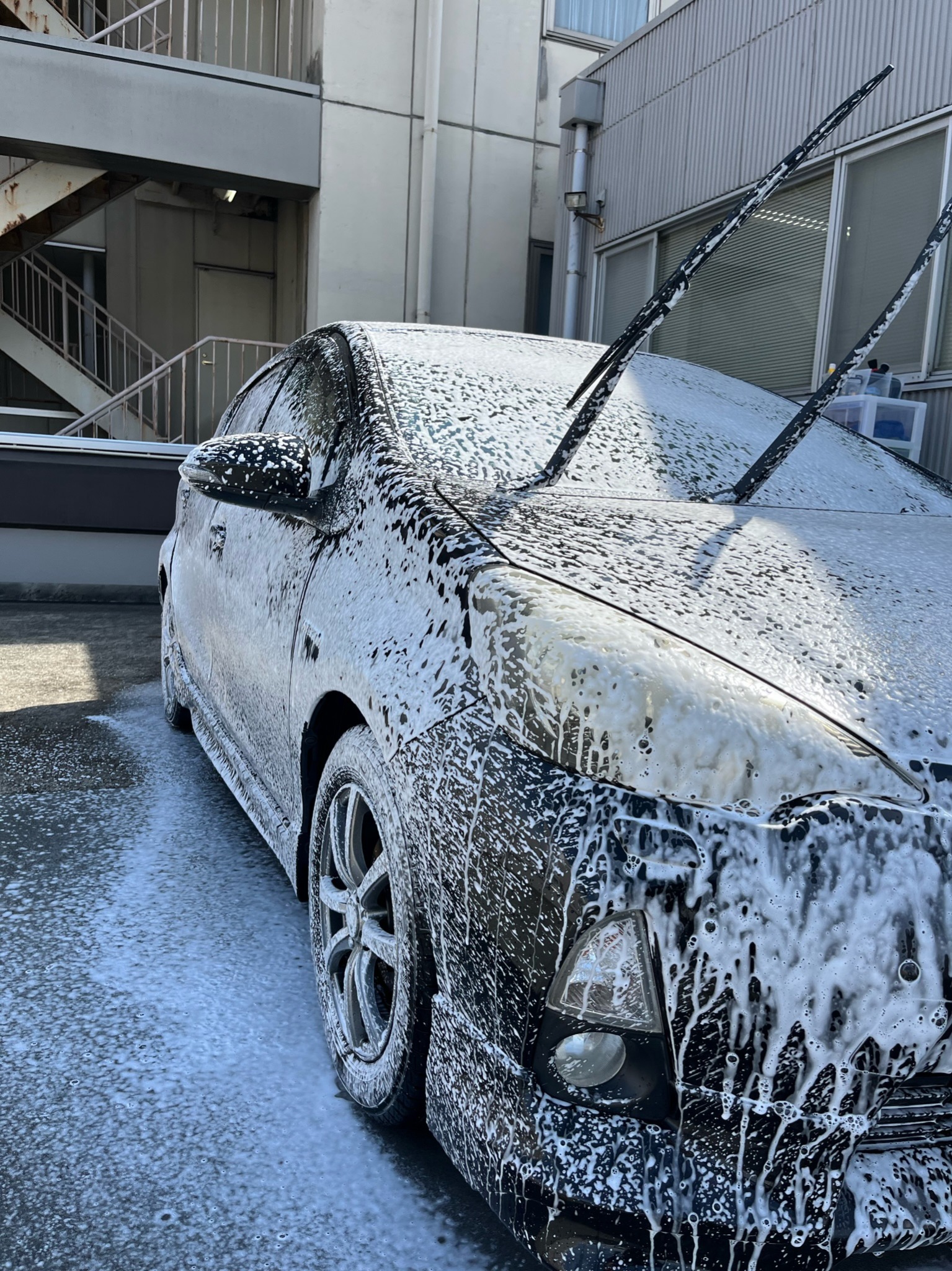 出張先の駐車場で泡洗車の作業を進めている様子